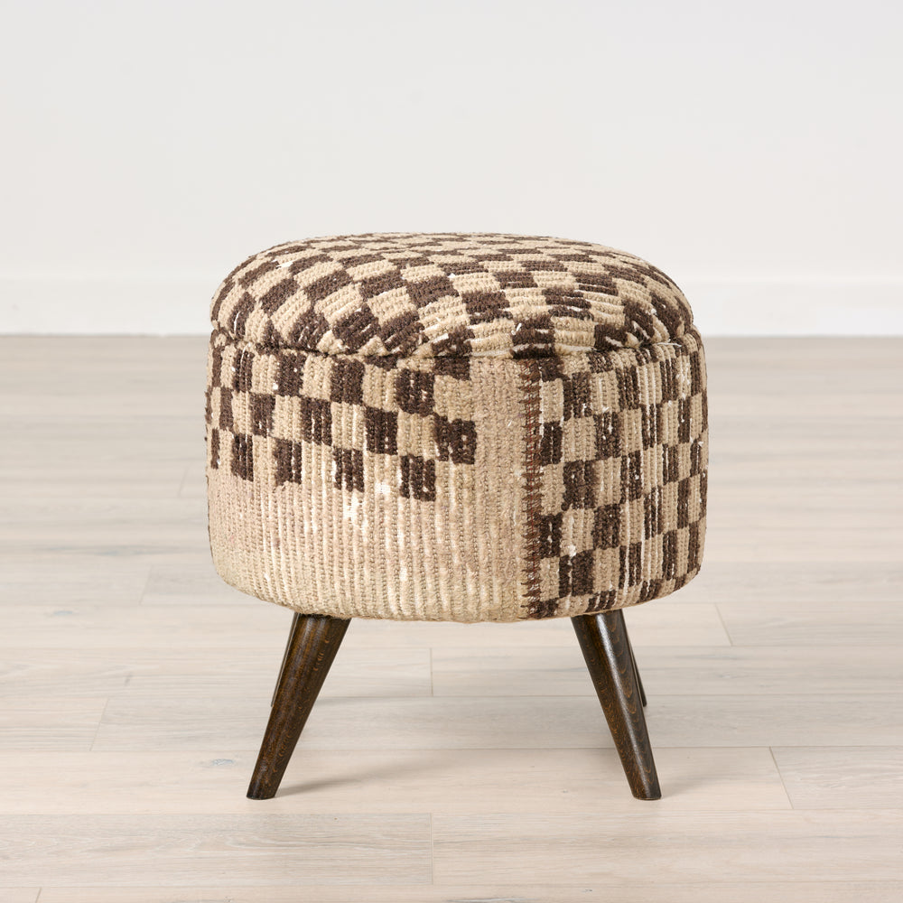 Round ottoman with a checkered pattern on a light wooden floor.