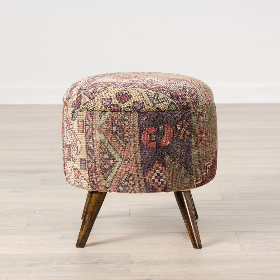 Patterned ottoman with wooden legs on a light wood floor.