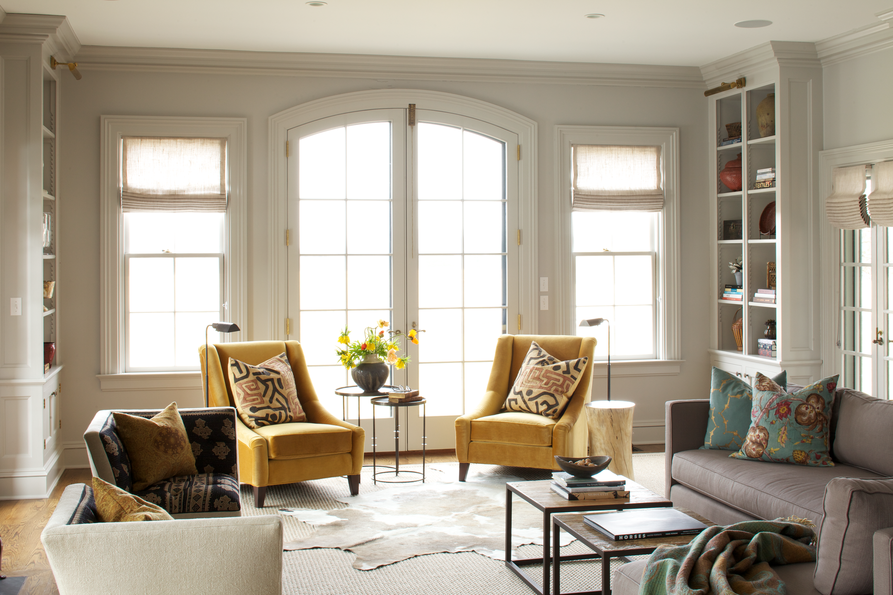 Bright styled living room with yellow chairs and french doors