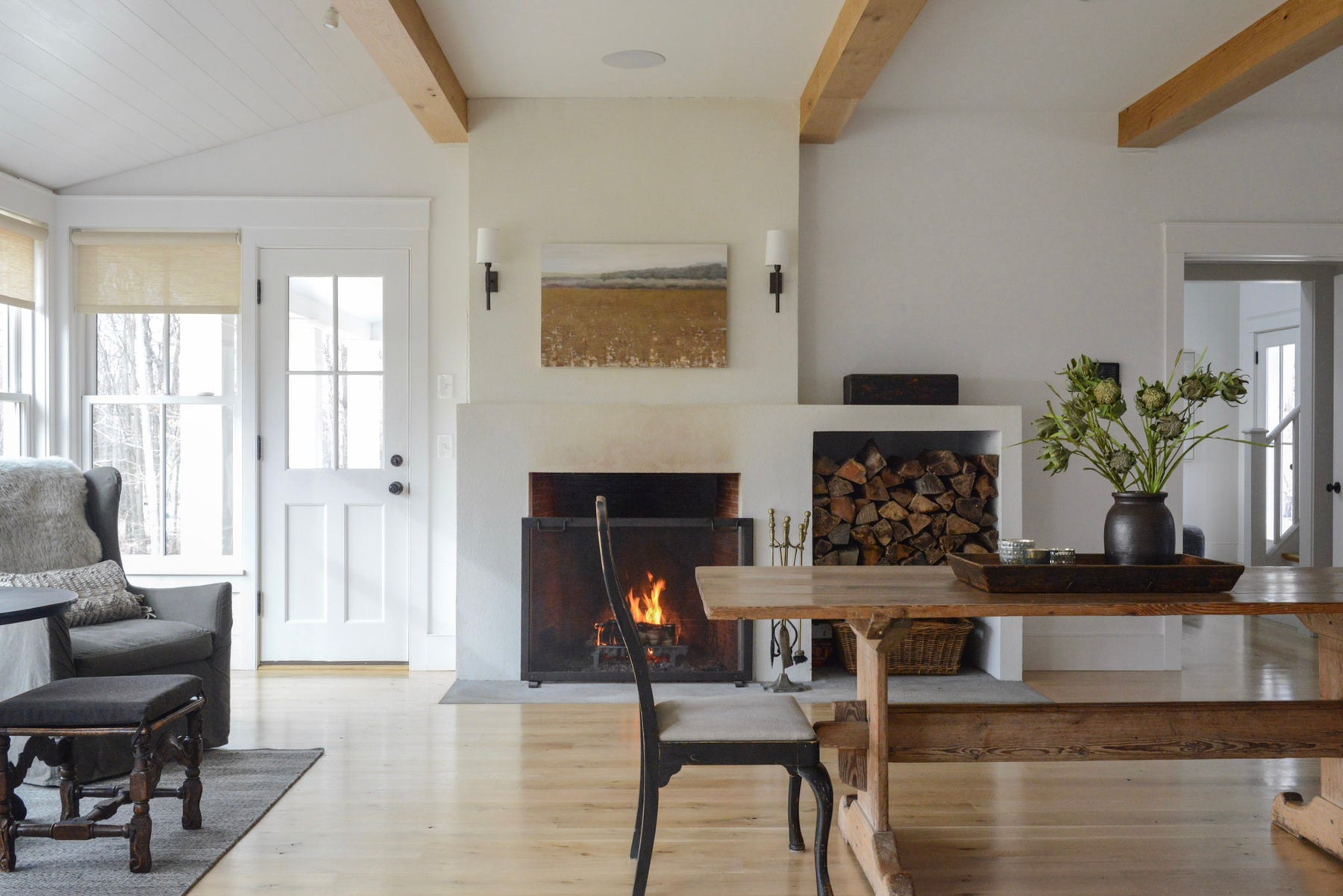 About Us | Styled winter living room with exposed beams, wood floors, and live fireplace