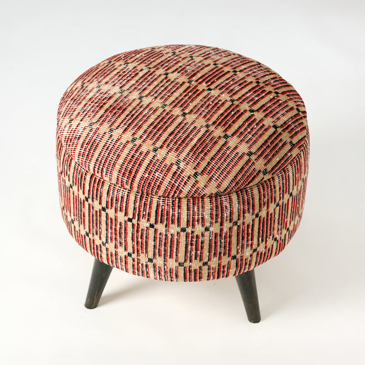 Round ottoman with patterned fabric and wooden legs on a white background