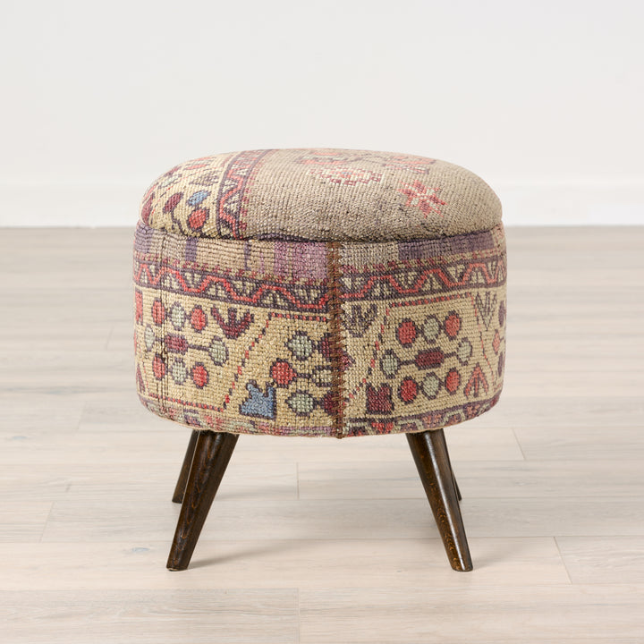 Round ottoman with patterned fabric cover on a wooden floor.Vintage Rug Small Ottoman 0725-A.