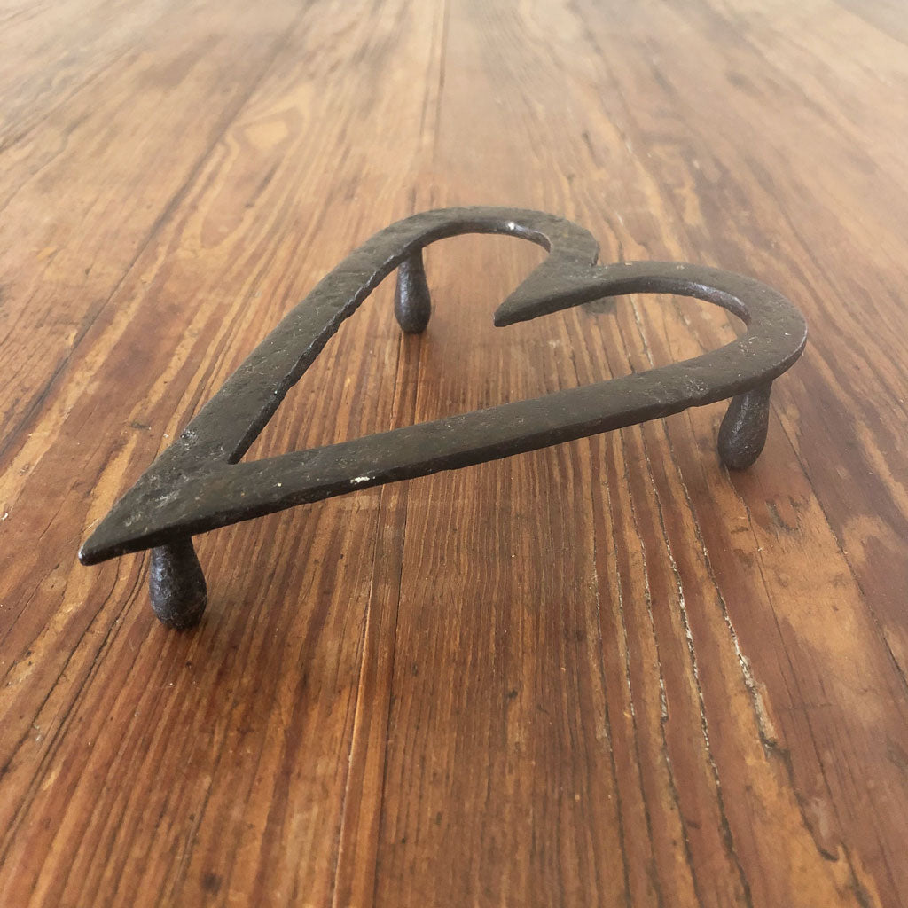 An antique cast offers iron heart trivet.