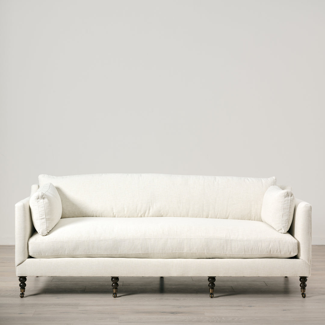 White sofa with decorative pillows on a light gray background