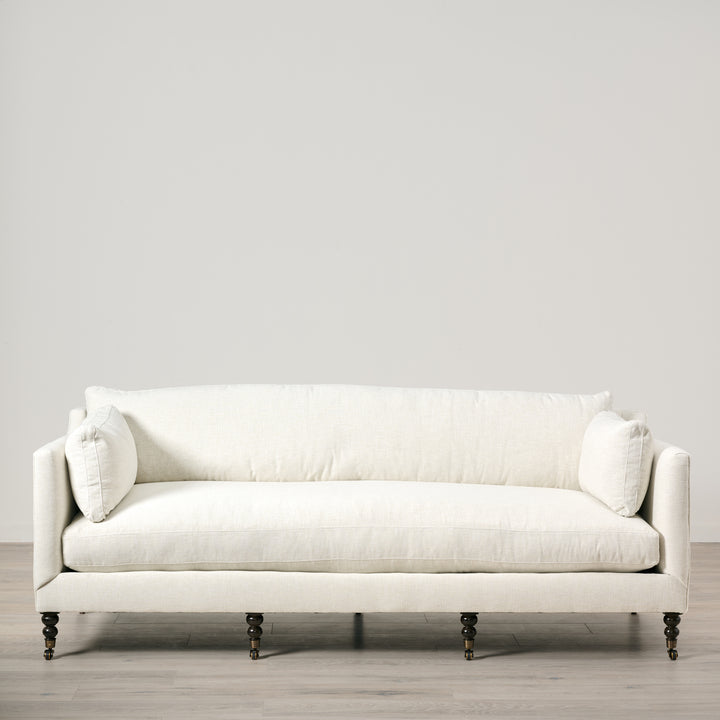White sofa with decorative pillows on a light gray background