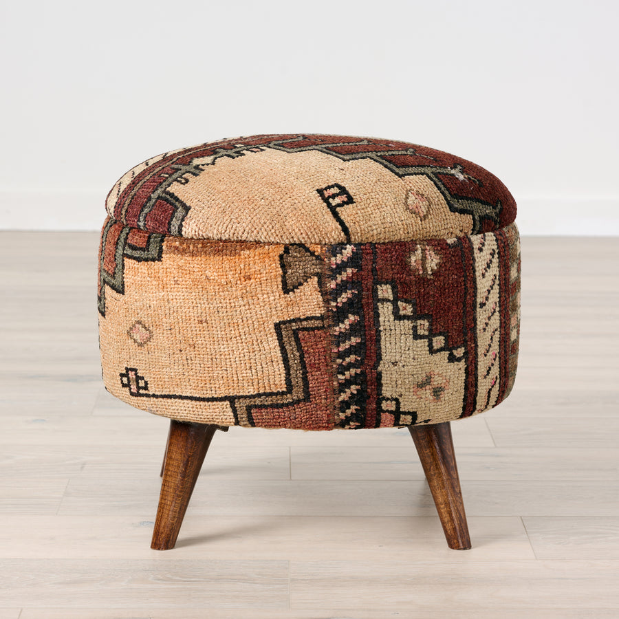 Round ottoman with patterned cushion and wooden legs on a light wooden floor.