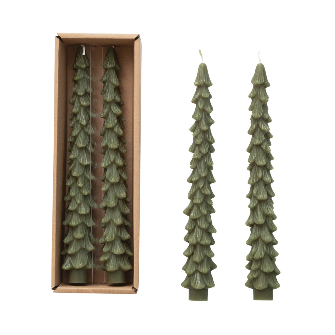 Set of green pine tree-shaped candles with one candle outside its packaging on a white background.