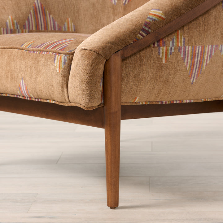 Brown upholstered chair with wooden legs on a light wood floor