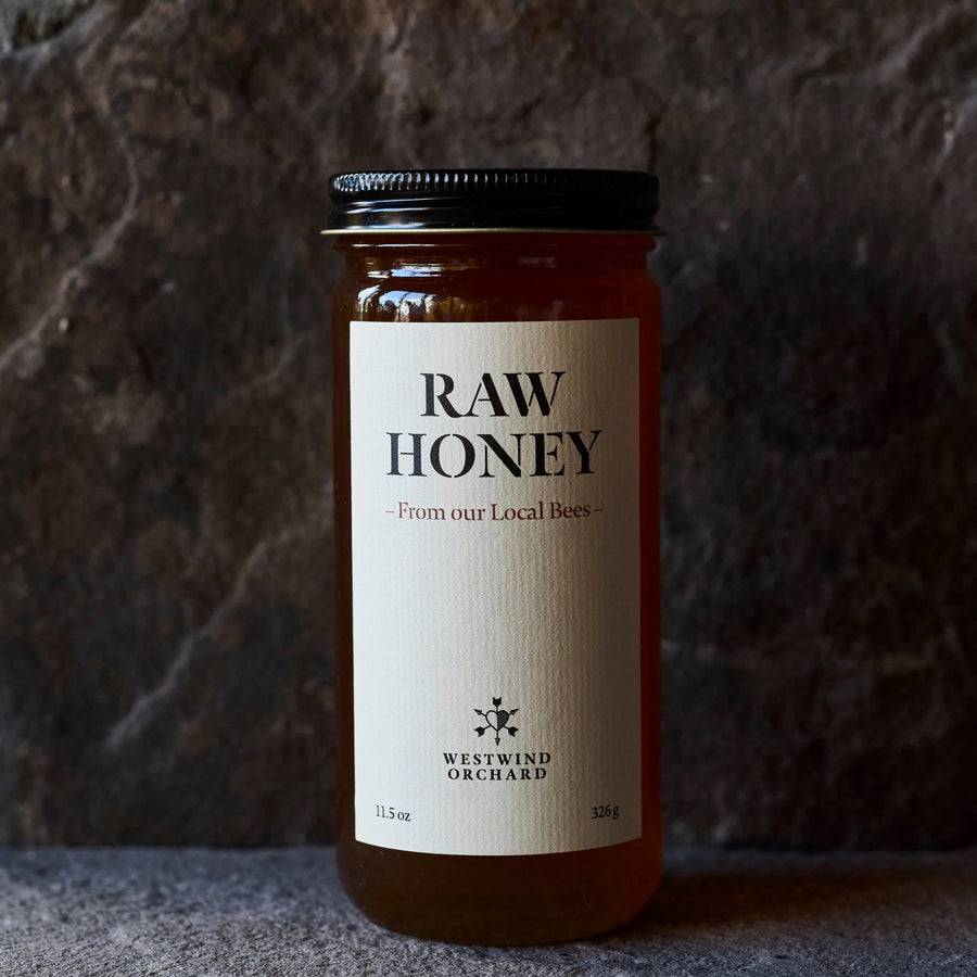 Jar of raw honey with a label on a textured surface