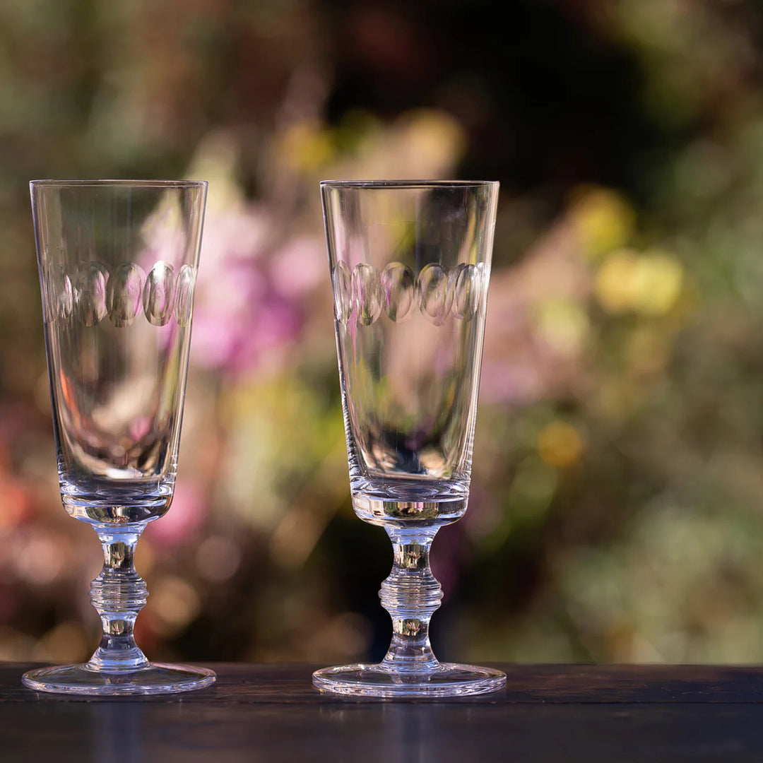 Two clear glasses with engraved text on a blurred natural background