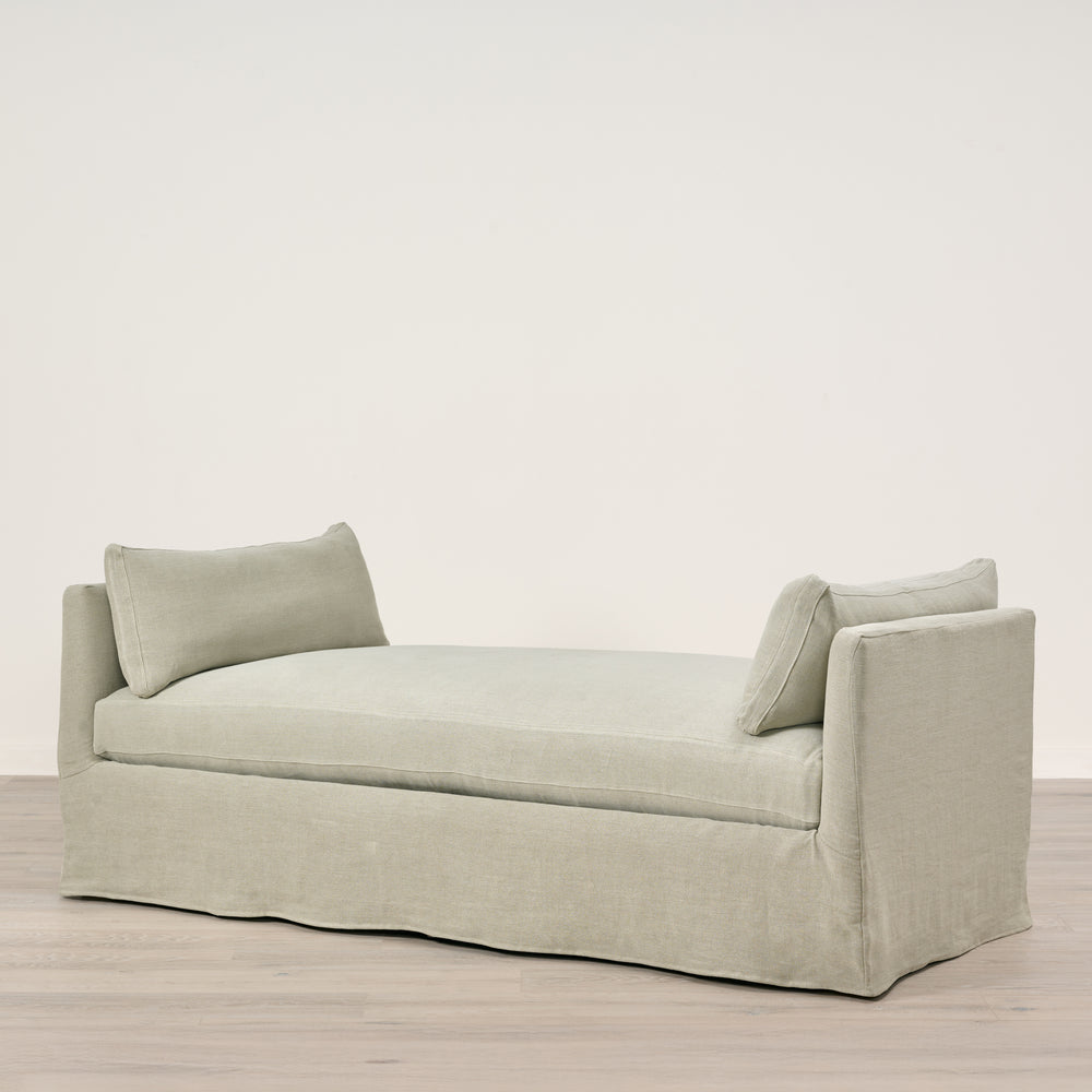 Light gray sofa with two cushions on a wooden floor and light beige wall background