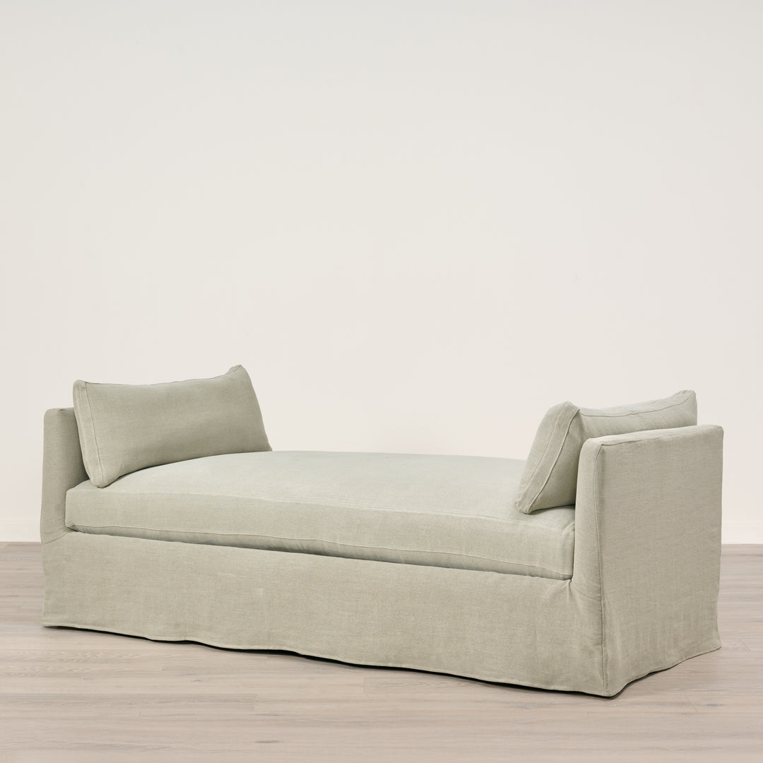 Light gray sofa with two cushions on a wooden floor and light beige wall background