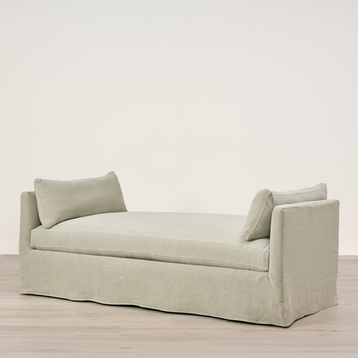 Light gray sofa with two cushions on a wooden floor and light beige wall background
