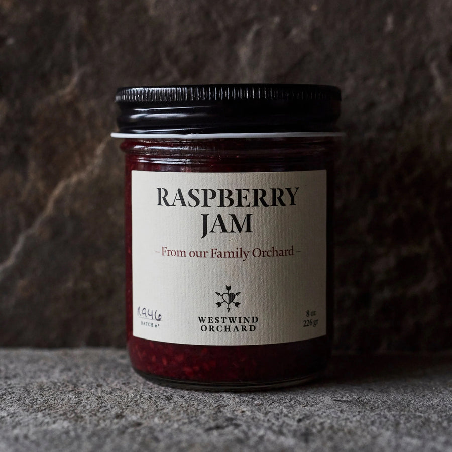 Jar of raspberry jam with a label on a textured surface