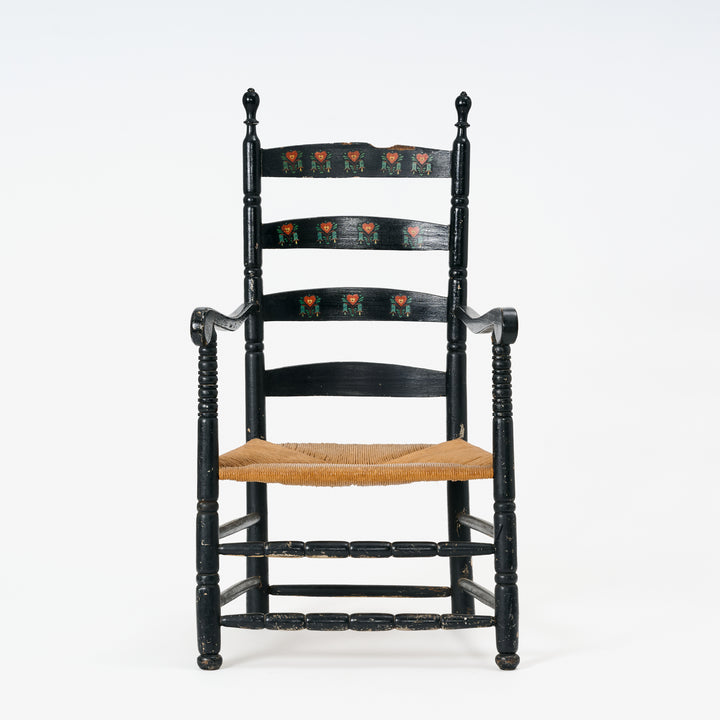 Black ladder-back chair with a woven seat on a white background