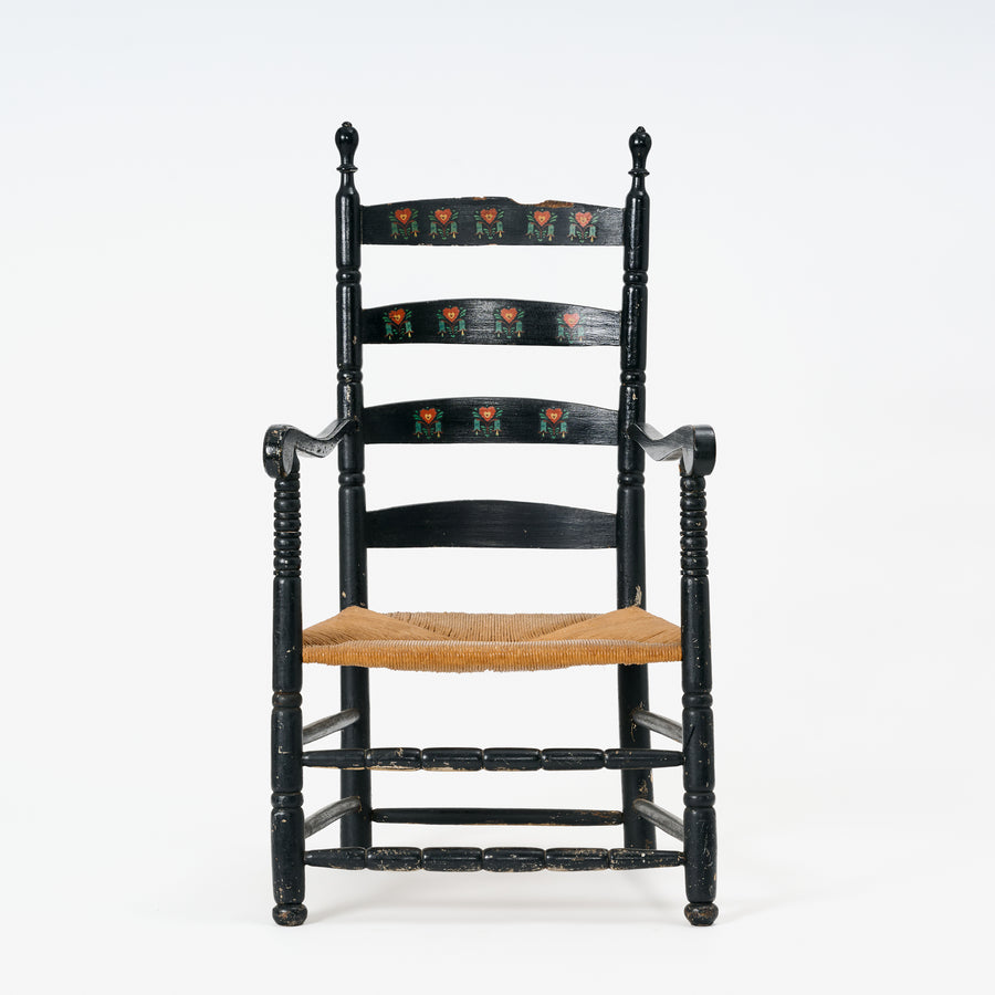 Black ladder-back chair with a woven seat on a white background