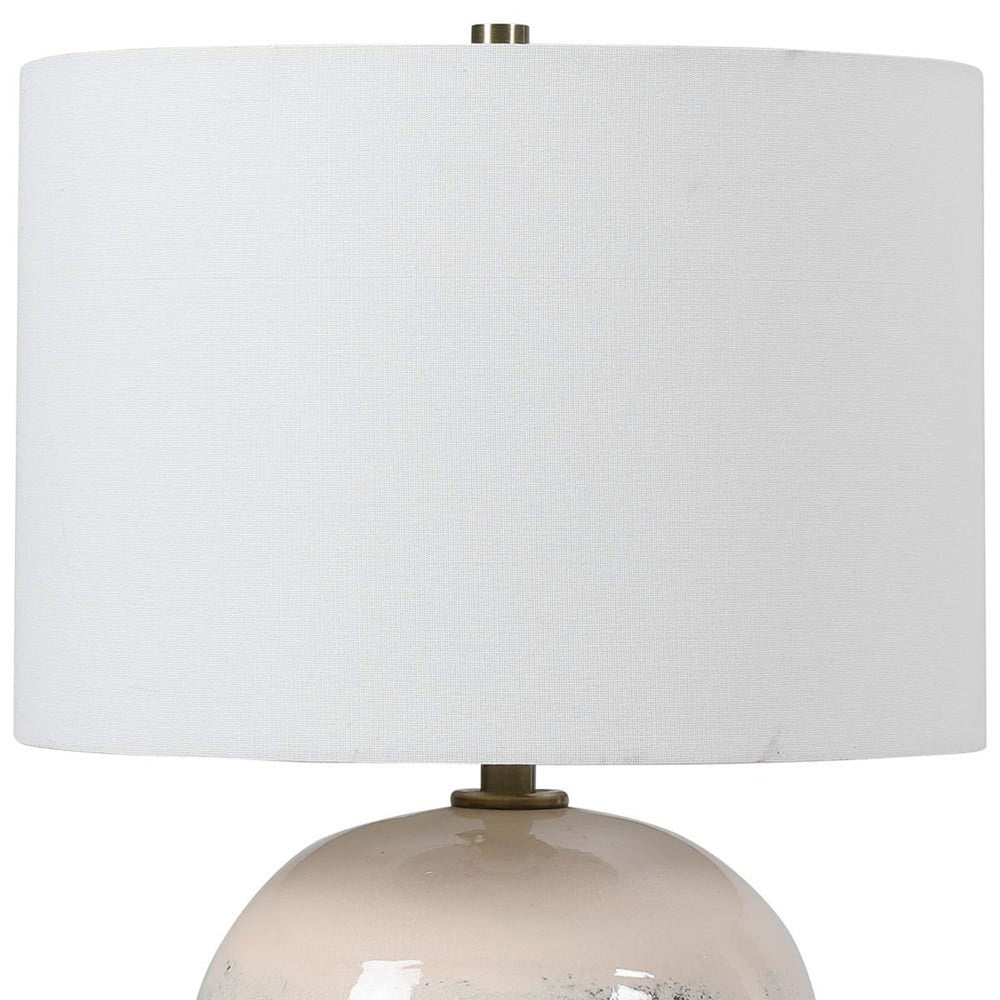 Table lamp with a white shade and beige base on a white background