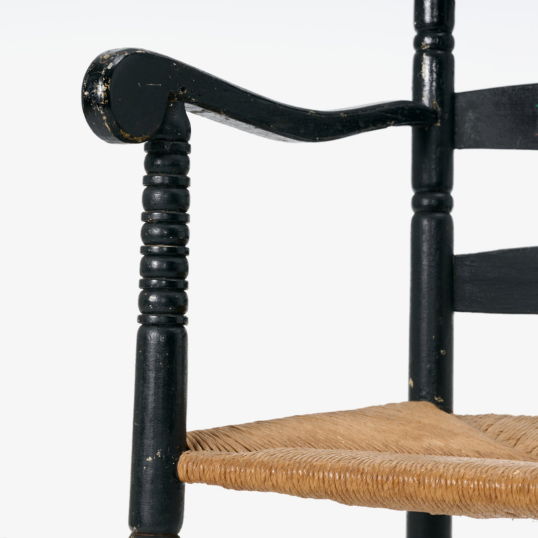 Close-up of a black wooden chair with woven seat on a white background