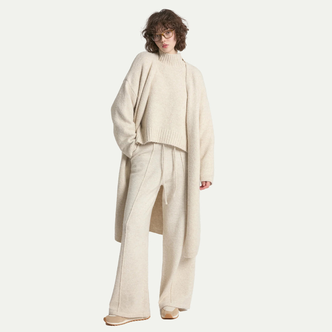 Person wearing a beige sweater and pants set on a white background