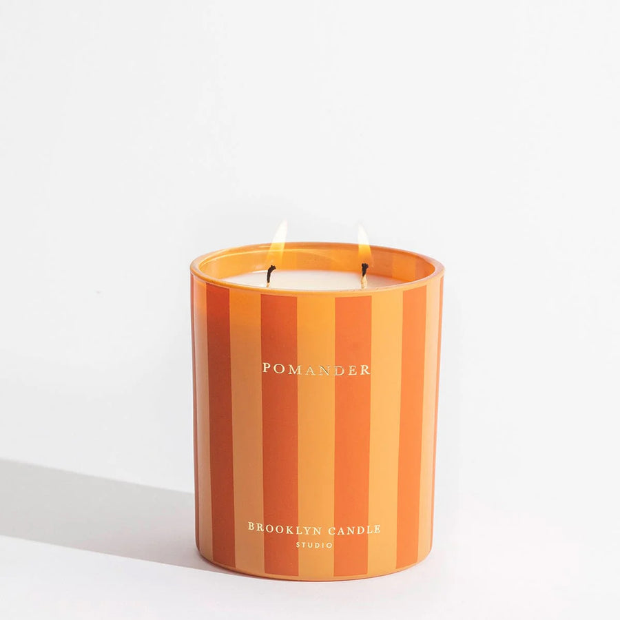 Striped candle with 'Pomander' branding on a white background