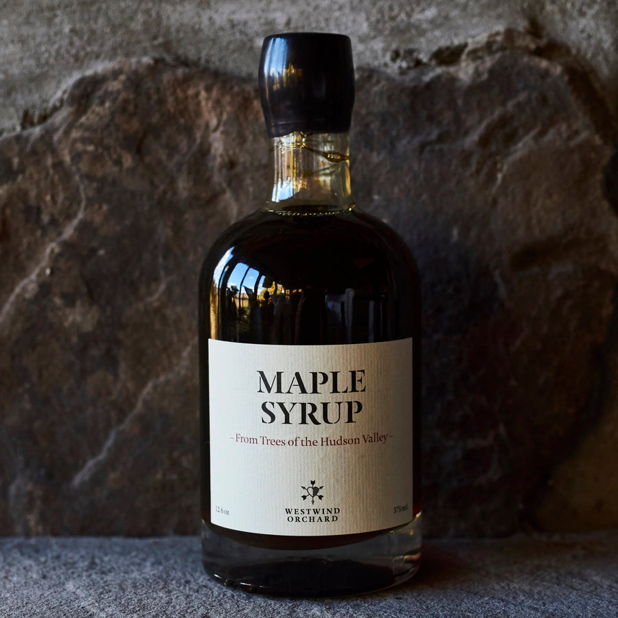 Bottle of maple syrup with a label against a stone background