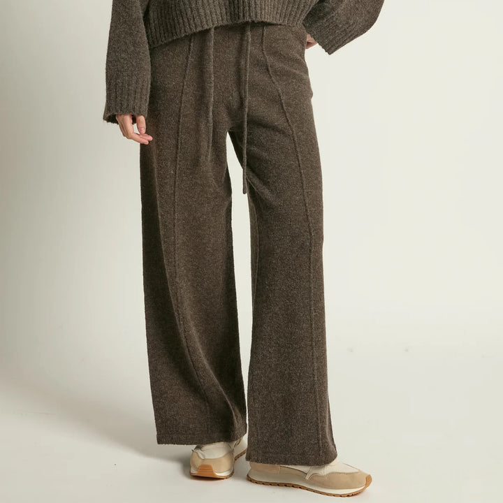 Person wearing brown wide-leg pants and a matching sweater on a plain background