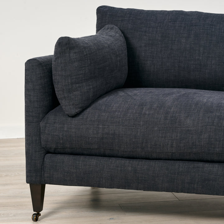 Gray sofa with a pillow on a wooden floor and light gray wall background