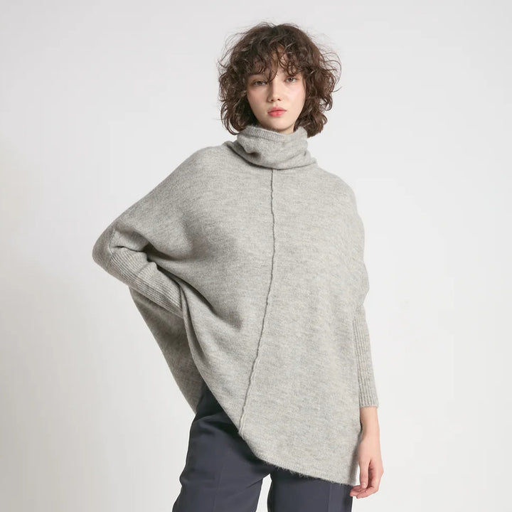 Person wearing a gray sweater against a plain background