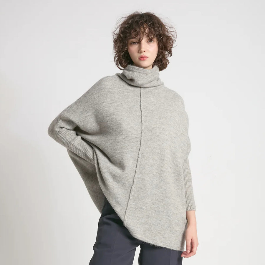 Person wearing a gray sweater against a plain background