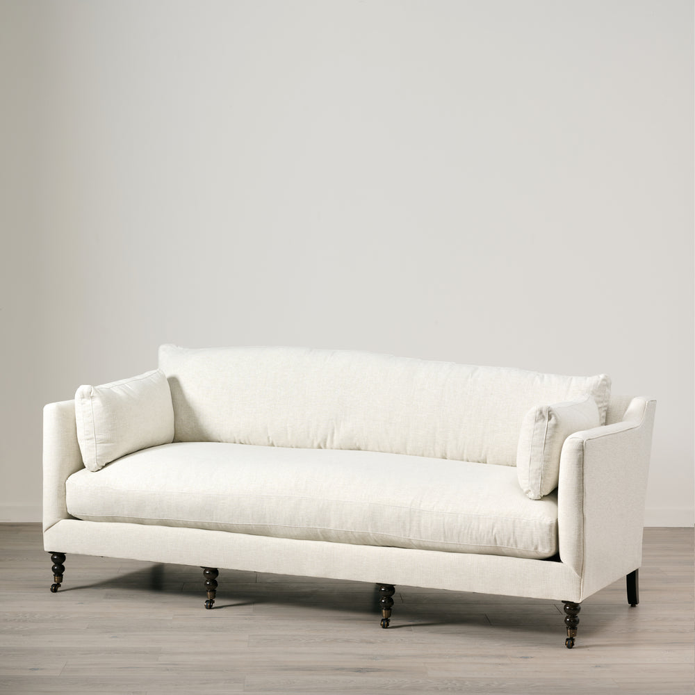 White sofa in a minimalistic room with a plain wall and wooden floor.