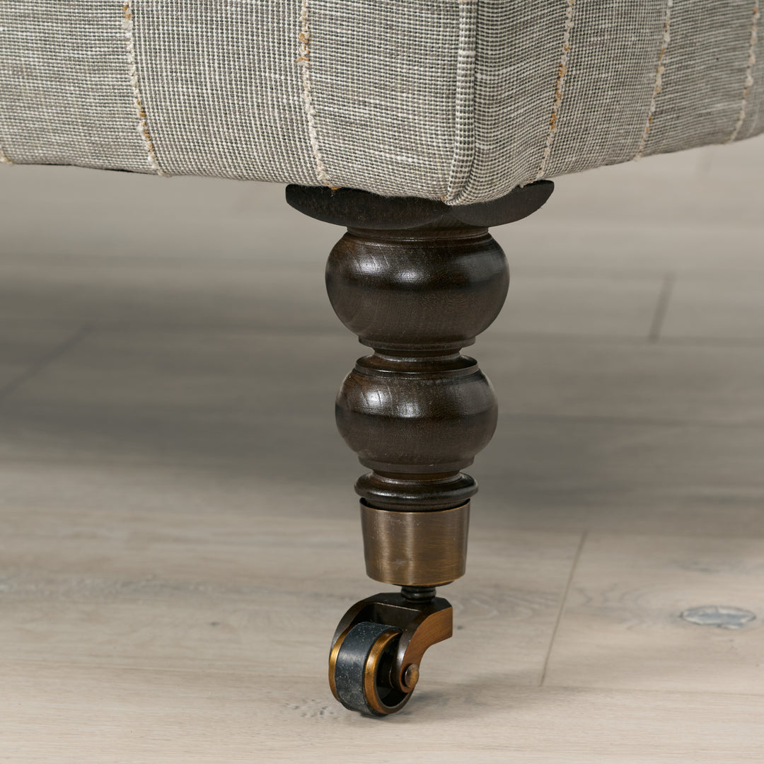 Close-up of a furniture leg with a decorative wheel on a wooden floor.