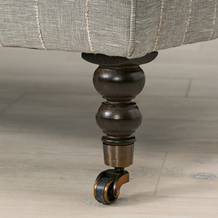 Close-up of a furniture leg with a decorative wheel on a wooden floor.