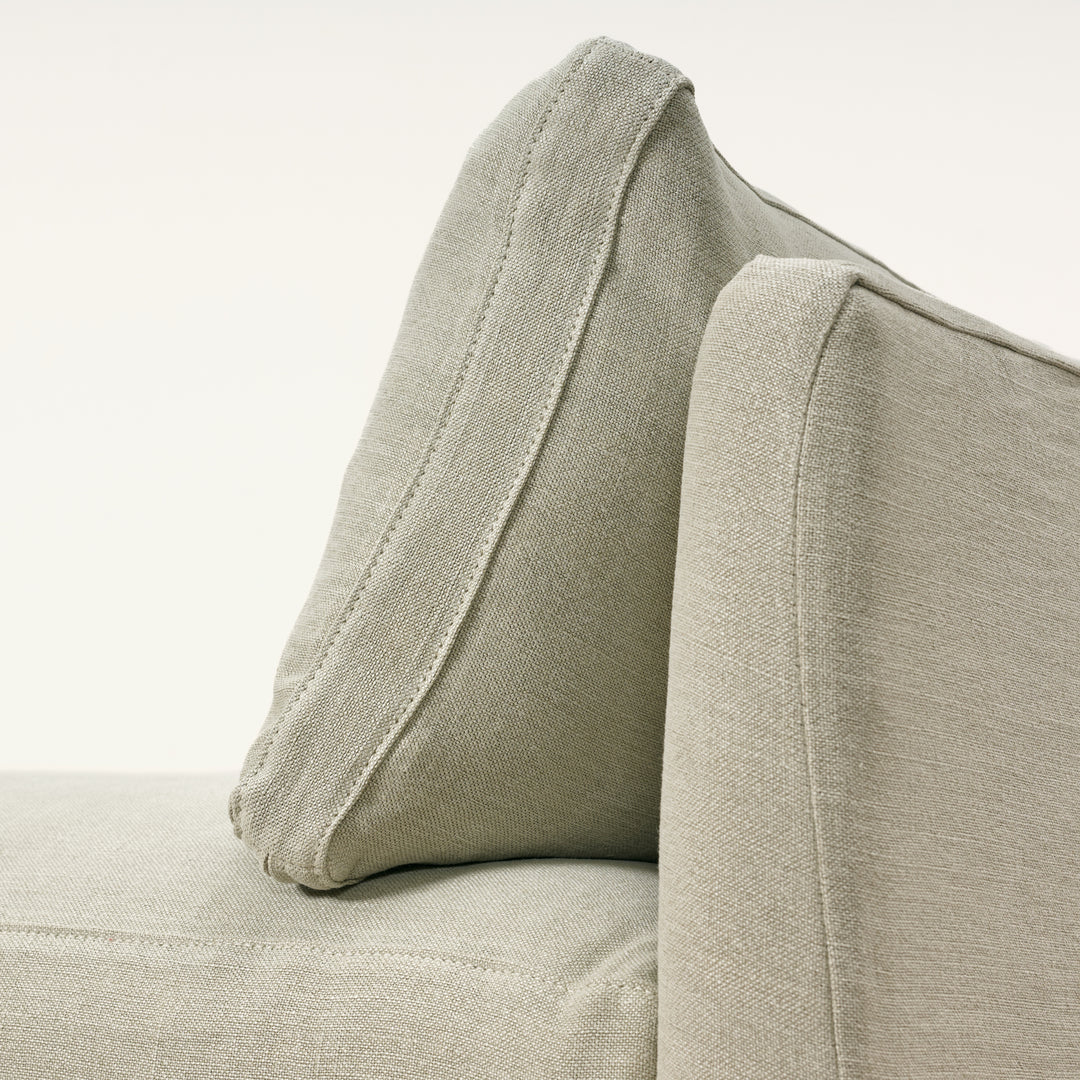 Close-up of a beige fabric armchair with a pillow on a light background