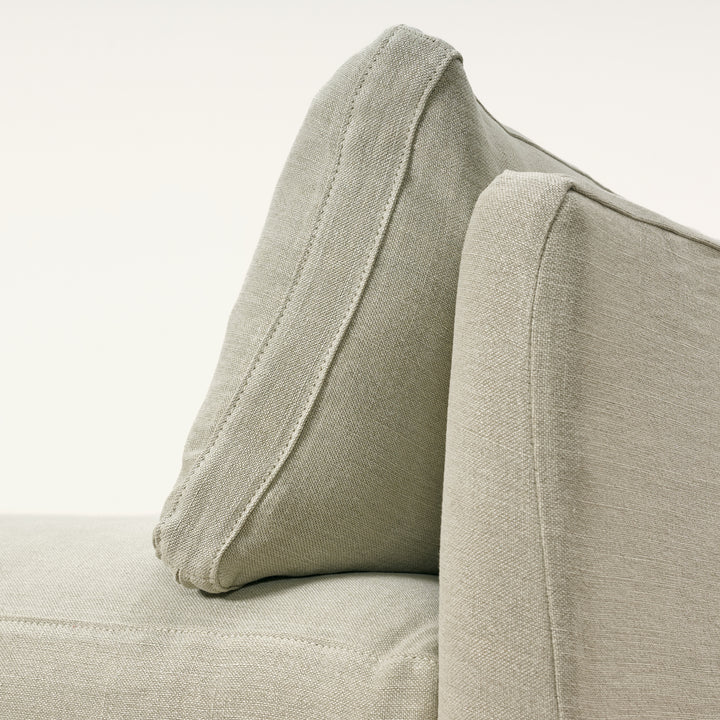 Close-up of a beige fabric armchair with a pillow on a light background