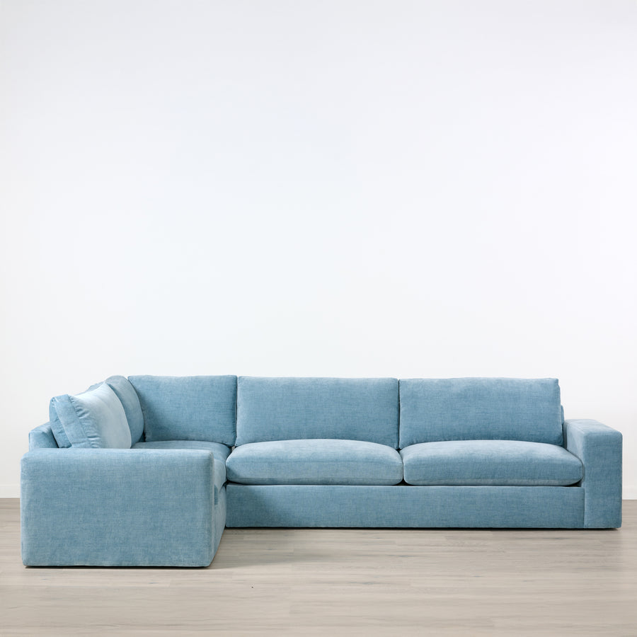 Blue sectional sofa on a wooden floor with a white background