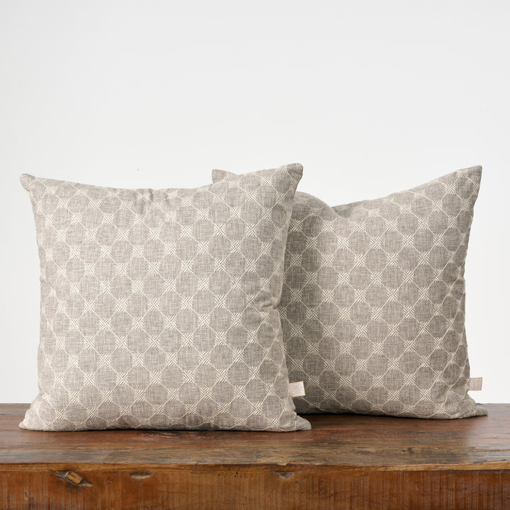 Two patterned pillows on a wooden surface with a white background
