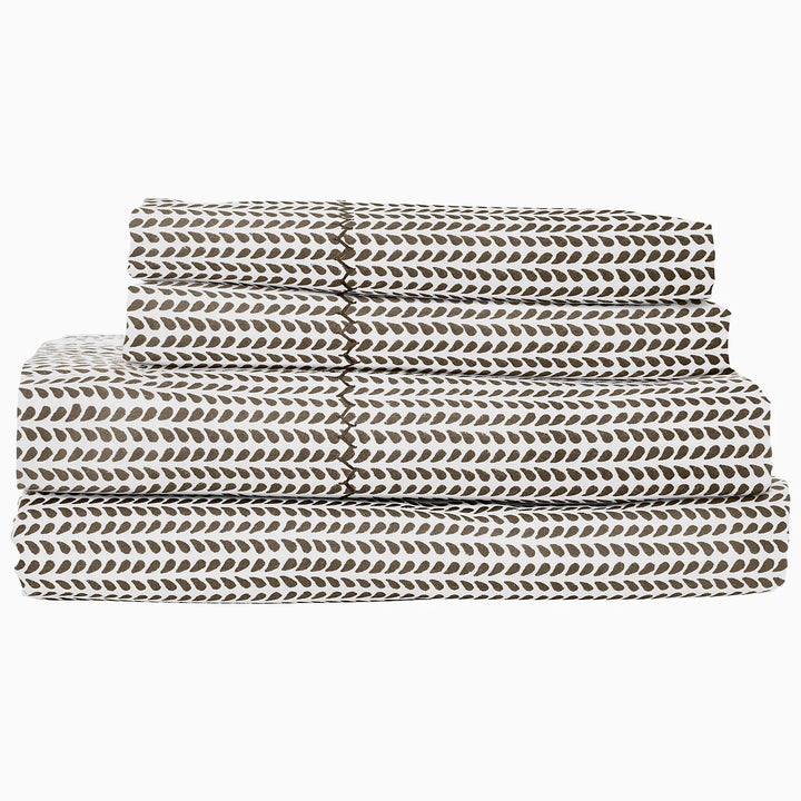 Folded bed sheets with a leaf pattern on a white background