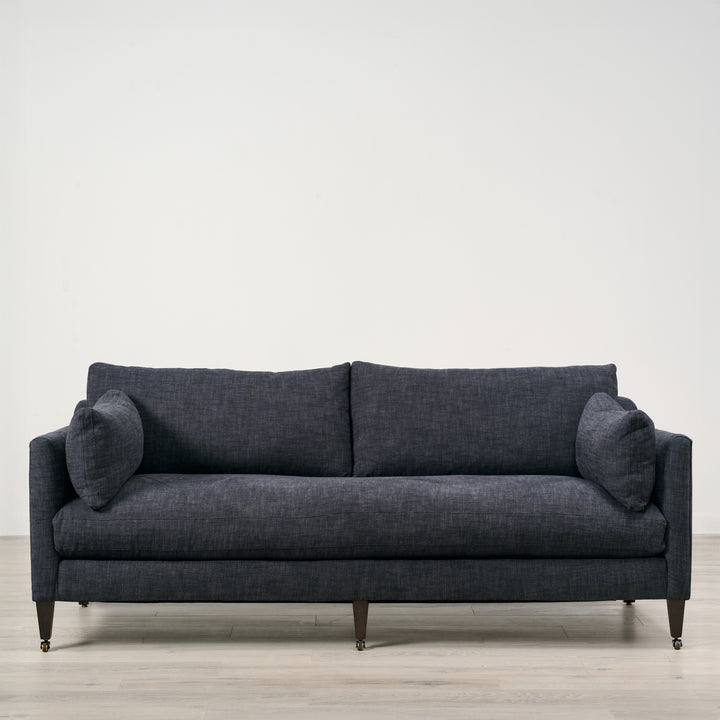 Gray sofa on a wooden floor with a white wall background