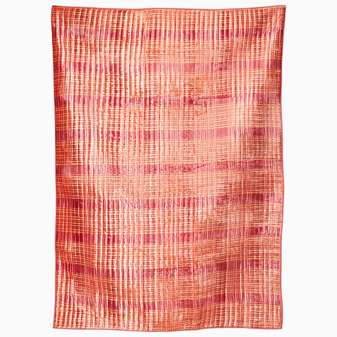 Textured fabric with a plaid pattern blanket in shades of red and orange on a white background