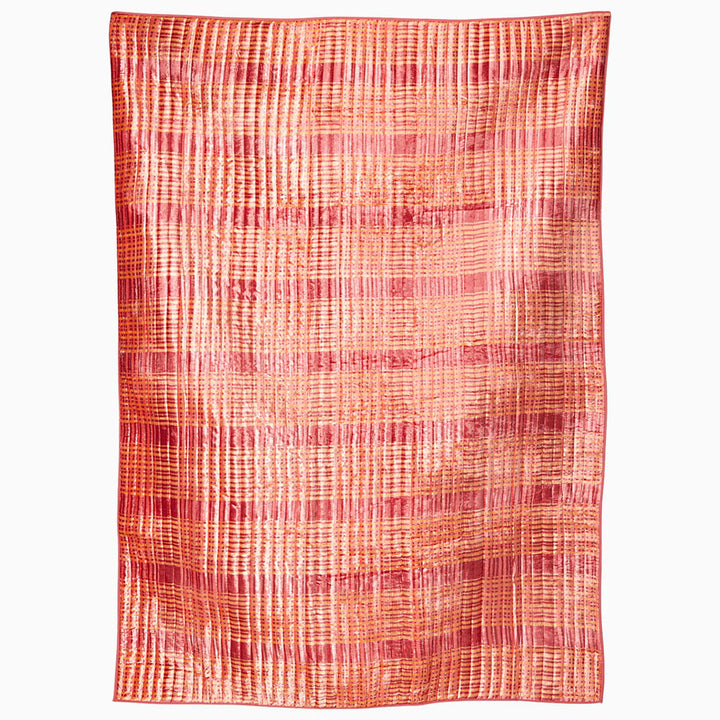 Textured fabric with a plaid pattern blanket in shades of red and orange on a white background