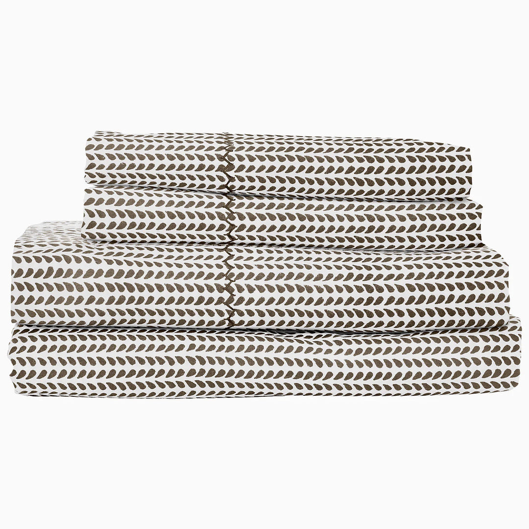 Folded bed sheets with a leaf pattern on a white background