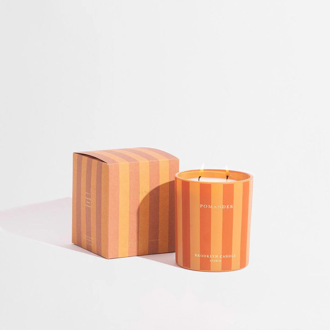 Striped candle with matching packaging on a light gray background