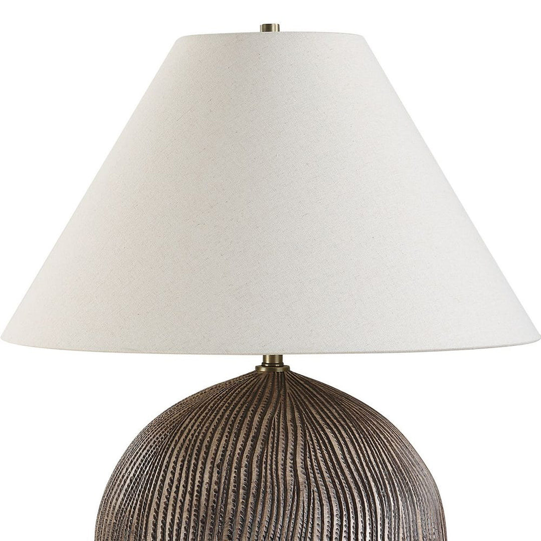 Table lamp with textured bronze base and white shade on a white background