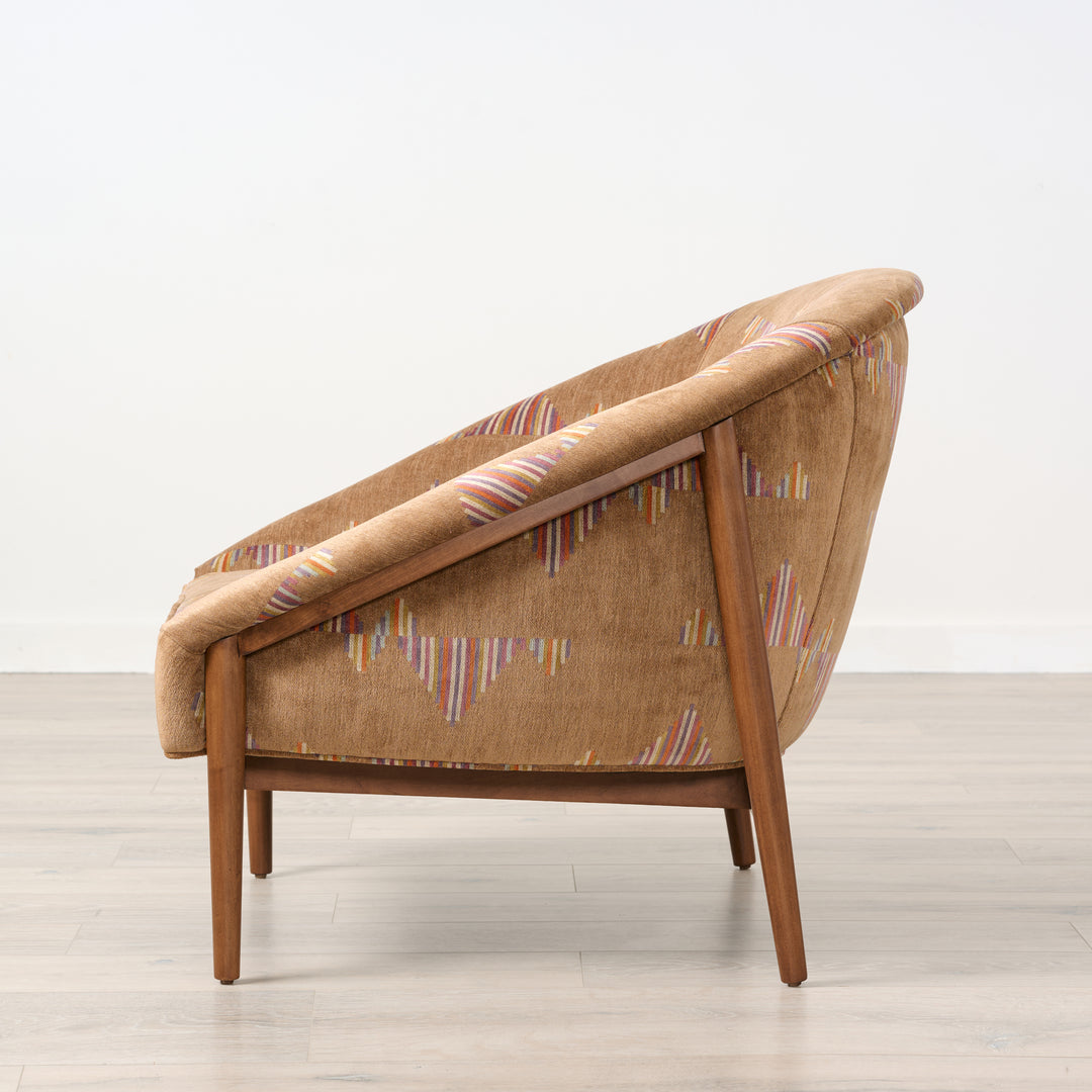 Brown armchair with patterned backrest on a light wooden floor and white background