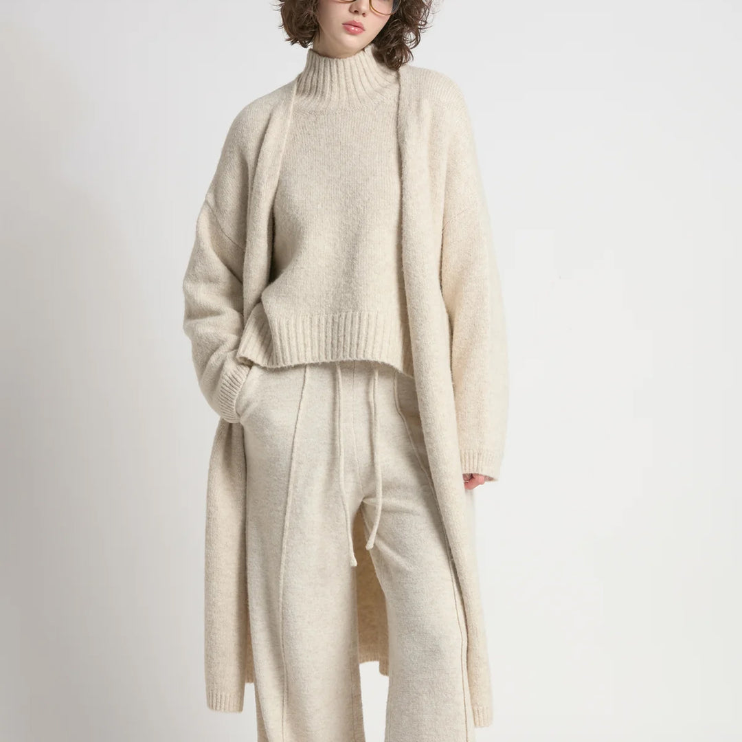 Person wearing a beige sweater and pants set on a white background