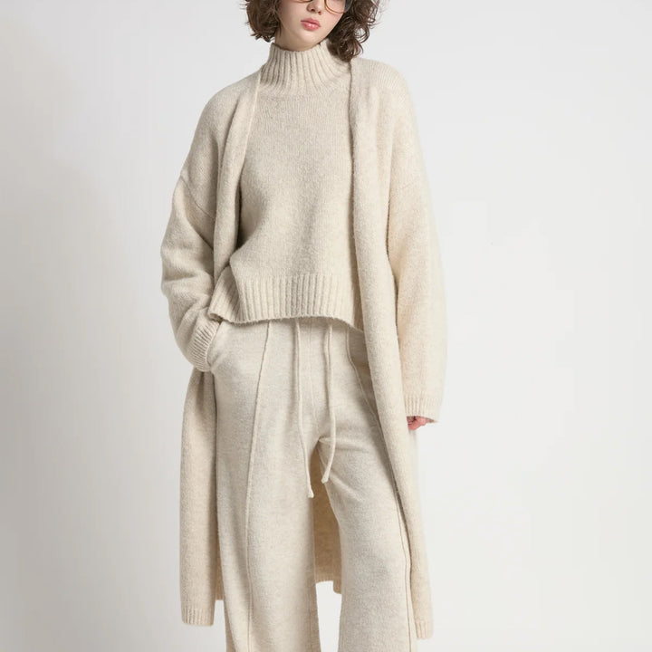 Person wearing a beige sweater and pants set on a white background