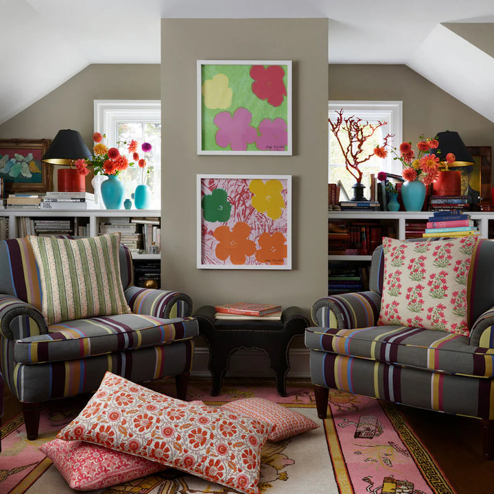 Living room with patterned armchairs, colorful artwork, and decorative pillows.