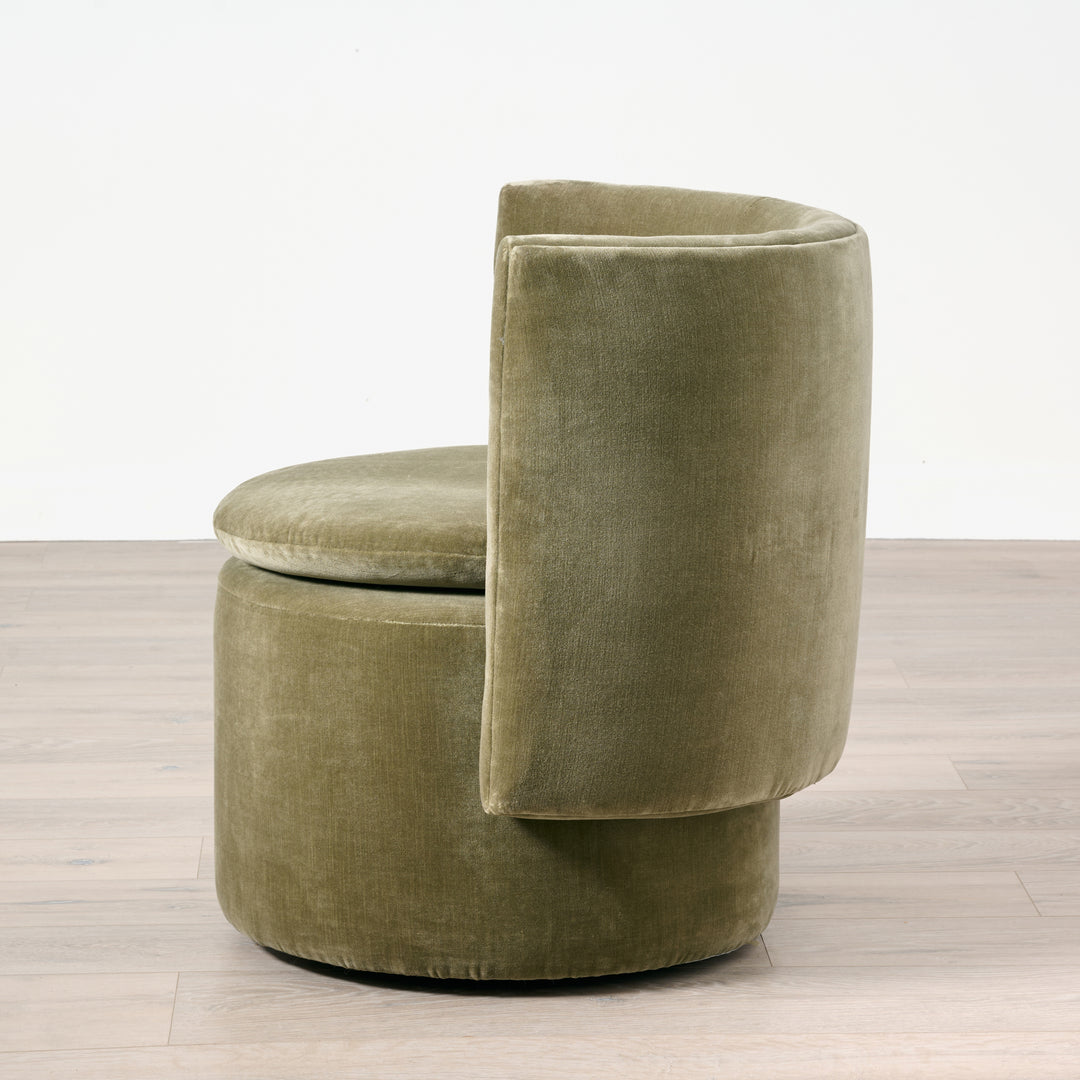 Green velvet chair on a wooden floor with a white background
