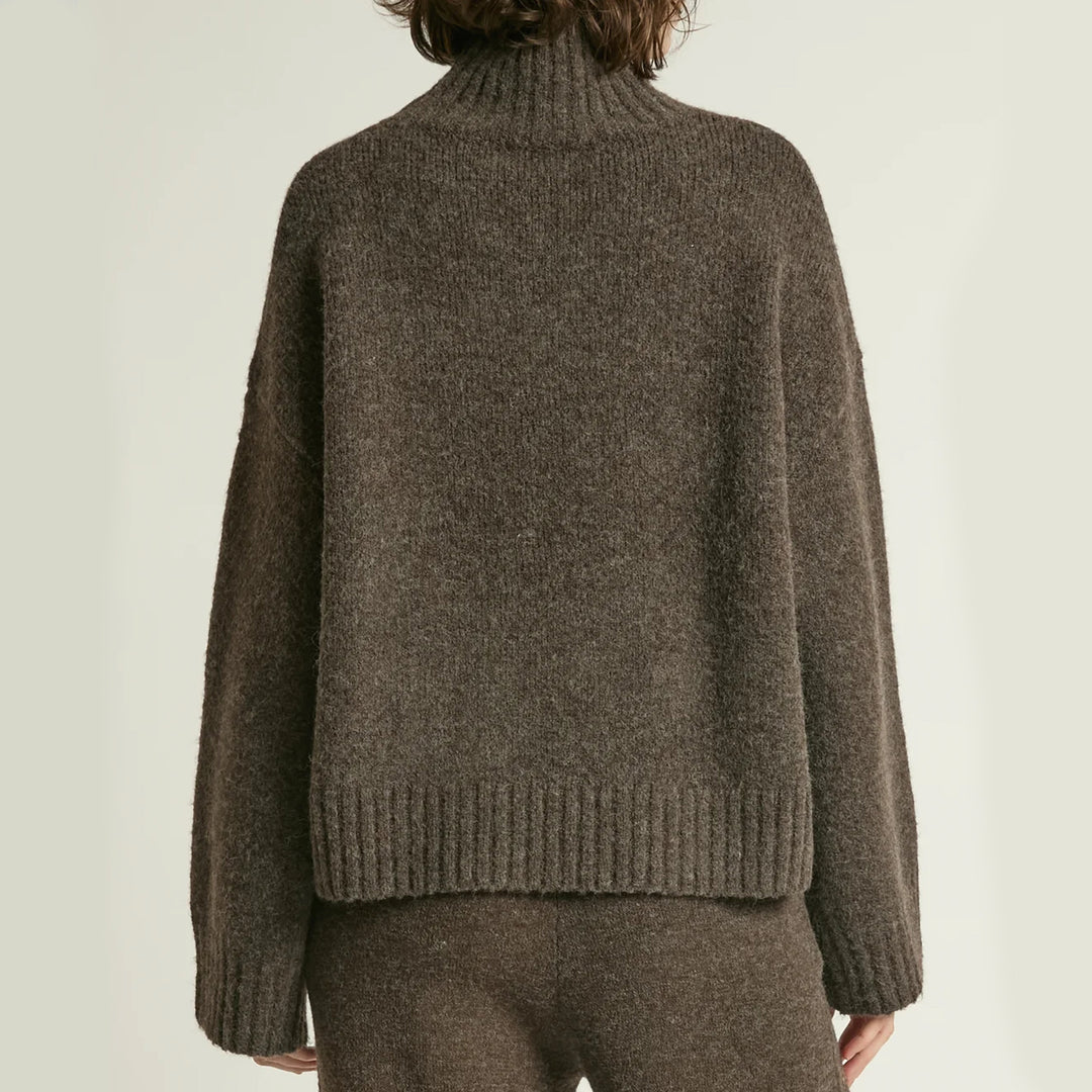 Brown knitted sweater worn by a person on a plain background