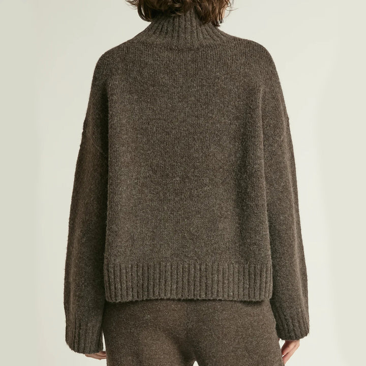 Brown knitted sweater worn by a person on a plain background